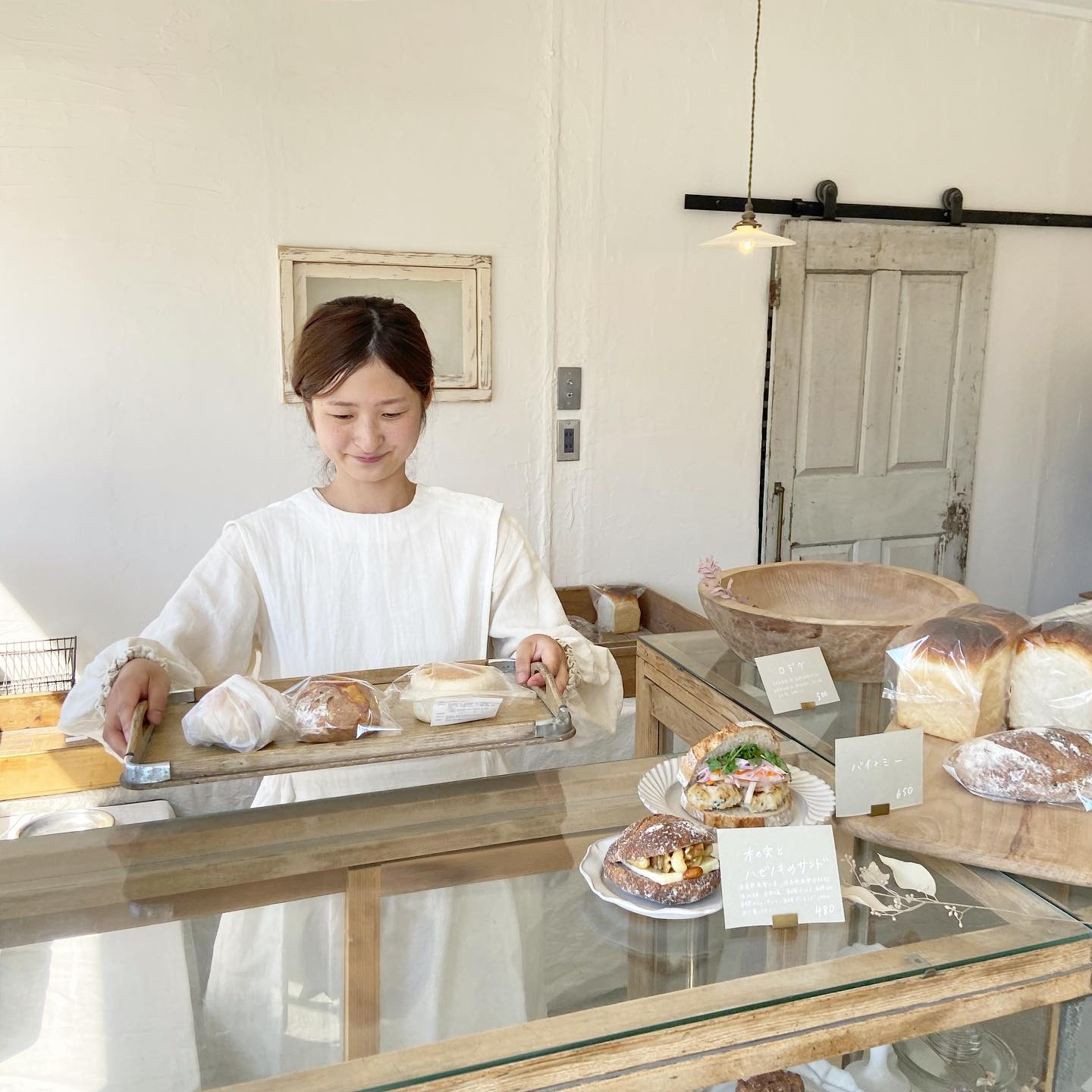 9月も後半で季節の移ろいを感じる毎日・来週23日から始まるオーダー会の準備や秋冬のニット類を鋭意製作中です・今年もあたたかくて心も癒される様な手触りのかわいいアイテムを皆様にご紹介できそうで自身もわくわくしています・お洋服も続々とお仕立て上がっていてイベント続きで中々ご紹介出来ずにいましたが今日はリボンワンピースのお話しです・・リボンワンピース・後ろにお行儀よく並んだ3つのリボンが印象的・遠い昔の女の子達が着るときに結びっこする絵がイメージできます・リボン結びを縦にならない様に、とびきり可愛く結べる様に、小さい頃に研究したおかげで私の自慢できない特技です・もちろん、苦手な方も大丈夫、左肩に付いたボタンは開閉できるので着る前に結び整えてからえいっとかぶって着ることができます・後ろの腰から下の貝ボタンも開けられるのでコーディネートによっては途中まで開けたり全開にして中のスカートなど見せて着るのもかわいいです・・首周りの詰まり具合いや胸当てのラインもきりりと、クラシカルな雰囲気・写真はKIKONOのミューズNoufu @noufu.pain のあきちゃんです・このワンピースはNoufuの制服としてもお使いいただいていてあきちゃんのご希望など、相談して作ったアイテム・・Noufuさんは去年の12月に入間市にオープン以来、皆んなを虜にするパンとお人柄が魅力的すぎるパン屋さん・・来週23日(木)秋冬帽子のオーダー会初日はKIKONOに出張販売に来てくれますので着こなしなど参考にされてくださいね・・リボンワンピース・¥23100(税込)・モデル身長163cm・・